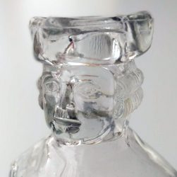 Photo image detail of a glass decanter shaped like George Washington, focusing on the head.