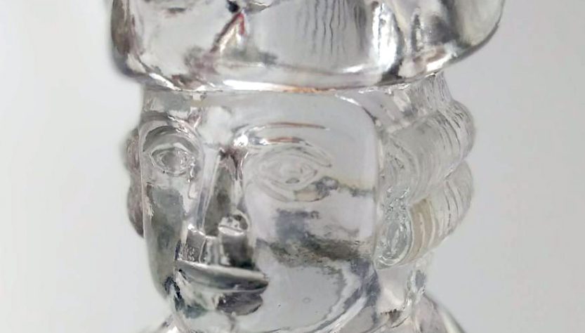 Photo image detail of a glass decanter shaped like George Washington, focusing on the head.